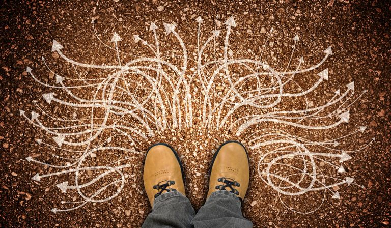 Yellow leather shoes and many winding chalky arrows on ground decision concept