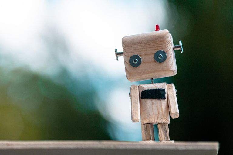 A wooden robot standing on a shelf.