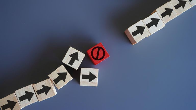 Wooden blocks with arrow and stop icon delays and disruptions stop the process critical error.