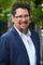 Headshot of Paul Ramos, CEO of Ridiculous Engineering, smiling and wearing glasses and a blue suit with a white shirt.